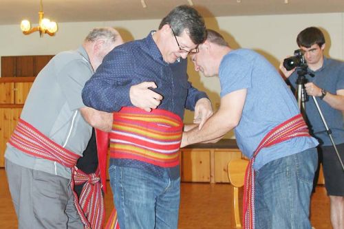 MP Mike Bossio is fitted with a rather large sash by High Land Waters President Scott Lloyd and Senator Robert Lloyd.